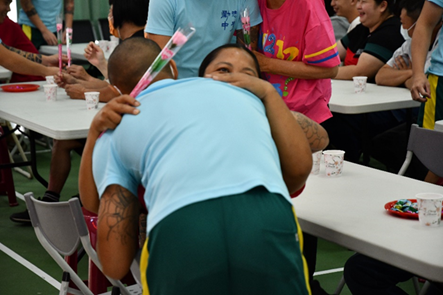 A student bows 90 degrees to his mother and presents her with a card and carnations